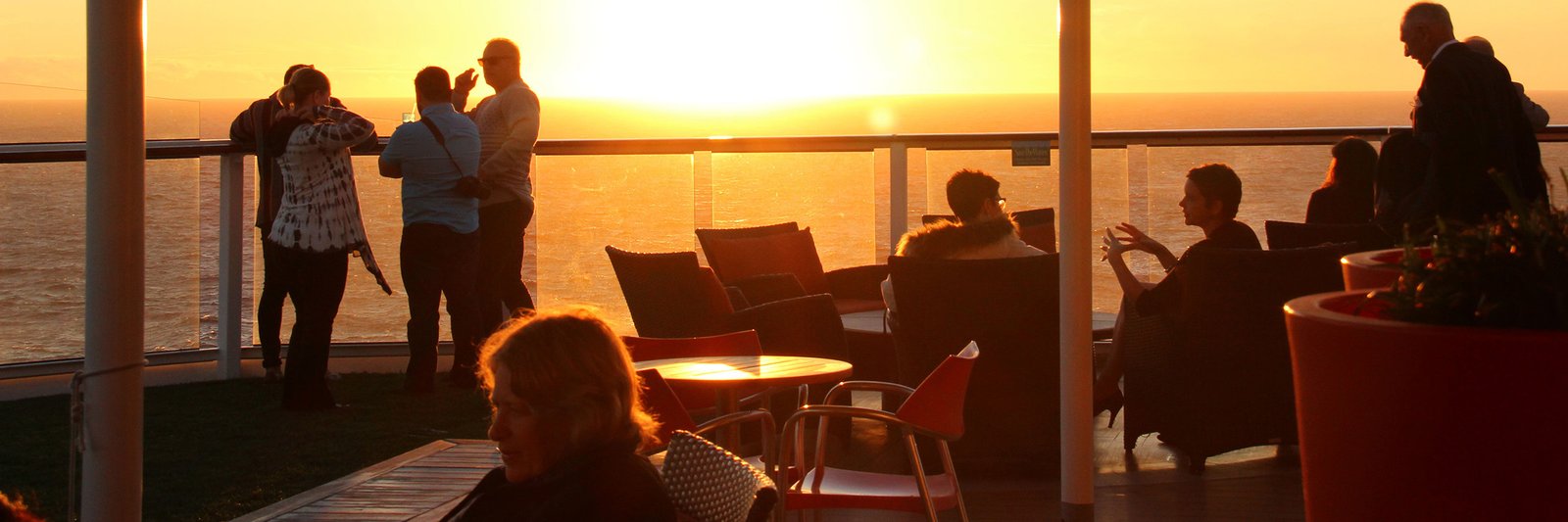 Group of travelers on cruise ship deck at sunset