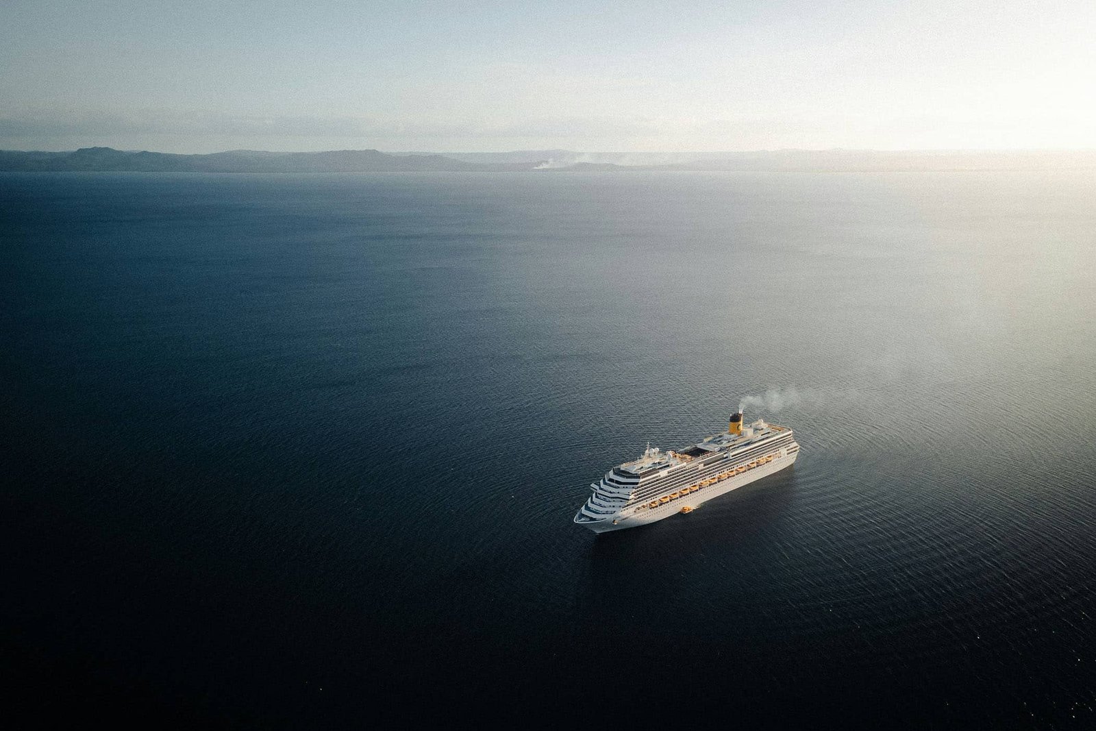 Aerial view of a cruise ship on open water at golden hour