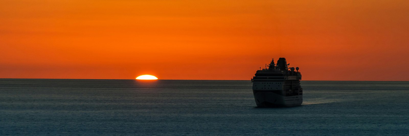 Cruise ship on open ocean at sunset